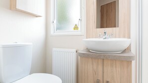Ein modernes Badezimmer mit Toilette, freistehendem Waschbecken und einem Holzschrank.