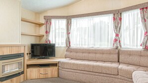 Ein gemütlicher Wohnbereich mit Sofa, Fernseher und Unterhaltungseinheit.