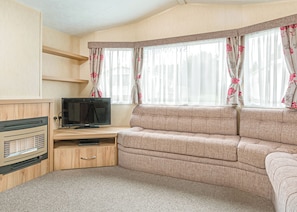 Una sala de estar acogedora con sofá, televisor y mueble de entretenimiento.