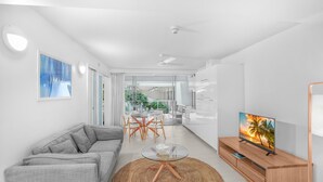 Una sala moderna con un sofá gris, una mesa de centro de cristal y un mueble bajo para el televisor de madera.