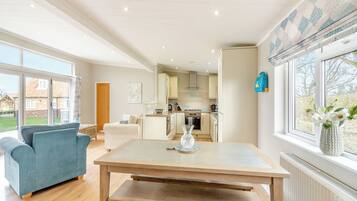 A spacious living area with a sofa, a dining table, and a kitchen in the background.