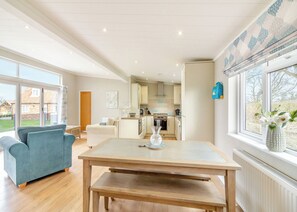 A spacious living area with a sofa, a dining table, and a kitchen in the background.