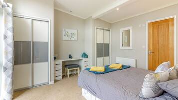 A bedroom with a bed, a desk, a chair, a wardrobe, and a bathroom.