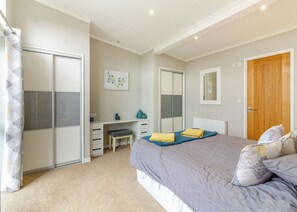 A bedroom with a bed, a desk, a chair, a wardrobe, and a bathroom.