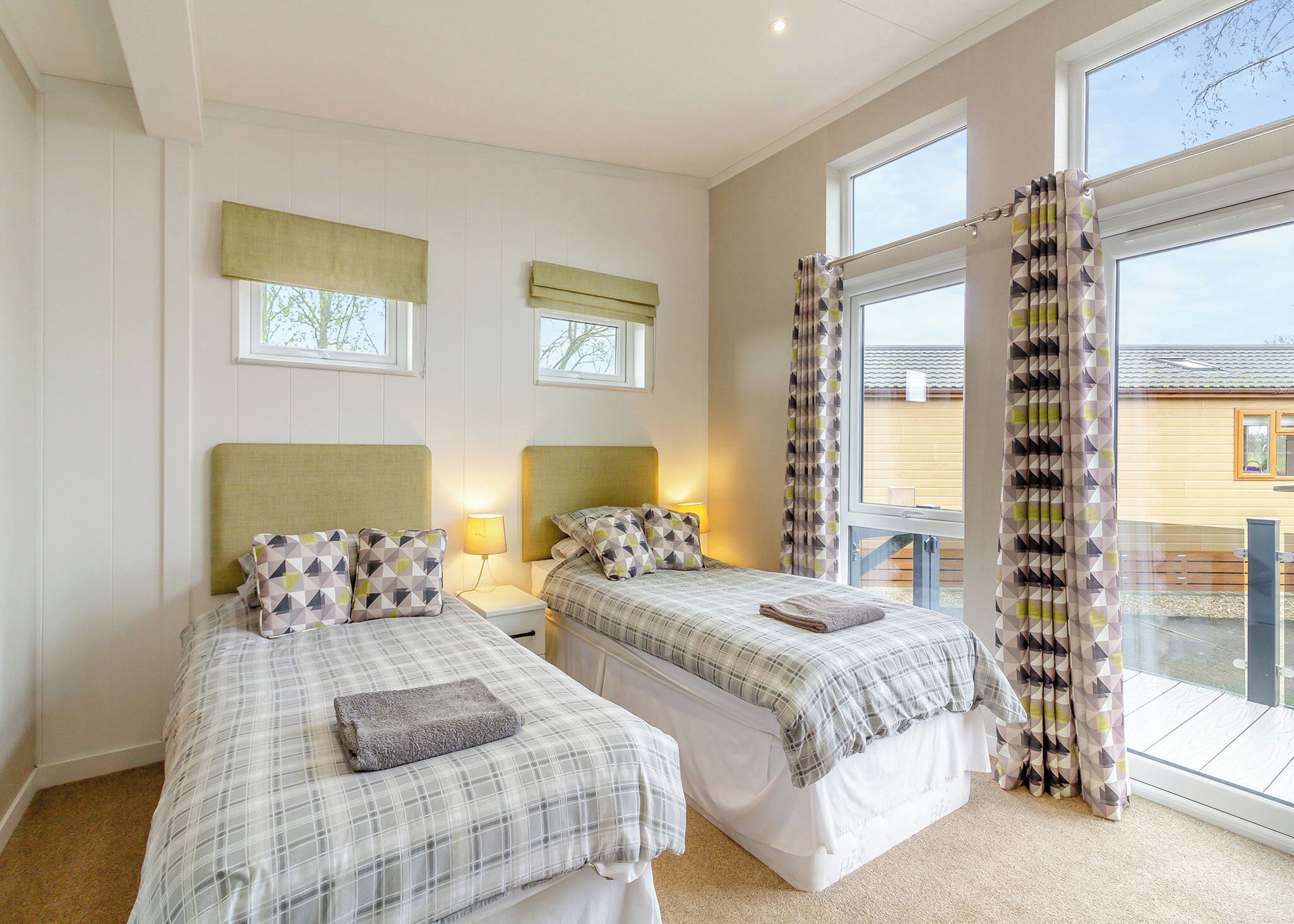A bedroom with two beds, a window, and a view of the outside.