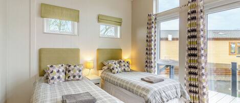 A bedroom with two beds, a window, and a view of the outside.