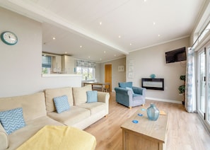 A living room with a sofa, a coffee table, and a TV mounted on the wall.