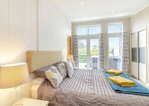 A bedroom with a bed, a bedside lamp, a window, and a view of the outdoors. - Luxury modern 2 Bedroom Lodge. (Swinethorpe, Nr Lincoln)