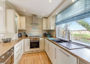 A modern kitchen with white cabinets, a gas stove, a built-in oven, and a window with a view of the outdoors.