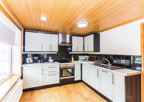A compact kitchen with white cabinets, a black countertop, and a wooden ceiling. - Outstanding, spacious and contemporary two storey lodge. (Hornsea)