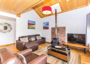 A living room with a leather sofa, a TV, a fireplace, and artwork on the walls. - Outstanding, spacious and contemporary two storey lodge. (Hornsea)