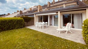 Une maison moderne dotée d’un patio, de meubles blancs et offrant une vue sur les maisons voisines.