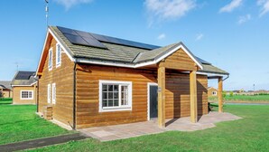 A log cabin with a solar panel roof, a covered porch, and a number '19' sign. - 4 bedroom accommodation in Hornsea (Hornsea)