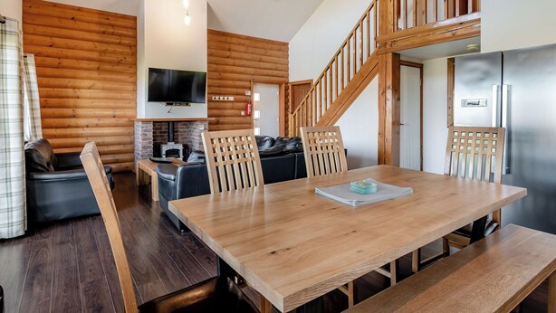 A wooden interior with a dining table, chairs, a sofa, a TV, and a staircase. - 4 bedroom accommodation in Hornsea (Hornsea)