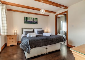 A bedroom with a bed, bedside tables, a painting, and a wooden ceiling.
