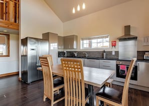 A modern kitchen with a dining area, stainless steel appliances, and a view of the outdoors.