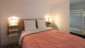 Un dormitorio con cama, lámparas de noche, cabecera de madera y una litera en la pared.