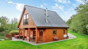 Een houten chalet met een schuin dak, een terras en een overdekte veranda.