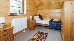 Een houten kamer met een bed, een kapstok en een raam.