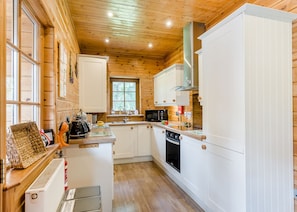A compact kitchen with wooden walls, white cabinets, a central island, and a window.