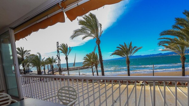 Un balcon avec vue sur la plage, les palmiers et la mer.