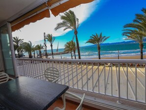 A balcony with a view of the beach, palm trees, and the sea.