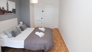 Une chambre à coucher avec un lit, un radiateur, une porte et un tableau représentant un paysage urbain.