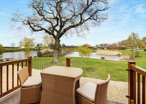 A deck with wicker furniture overlooking a pond and a residential area.