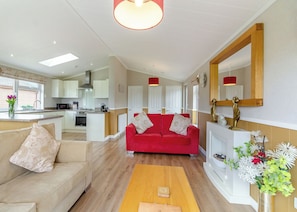 A modern kitchen with white cabinets, a red sofa, and a wooden floor. - Luxury lodge ideal for a couples romantic break away with a double driveway. (Swinethorpe, Nr Lincoln)