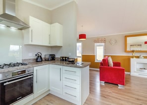 A modern kitchen with white cabinets, a red couch, and a wooden floor. - Luxury lodge ideal for a couples romantic break away with a double driveway. (Swinethorpe, Nr Lincoln)