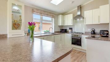 A modern kitchen with white cabinets, a granite countertop, a built-in oven, and a window with a view.