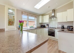 A modern kitchen with white cabinets, a granite countertop, a built-in oven, and a window with a view.