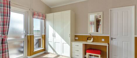 Une pièce avec une fenêtre, une porte, un miroir, un bureau et une chaise.