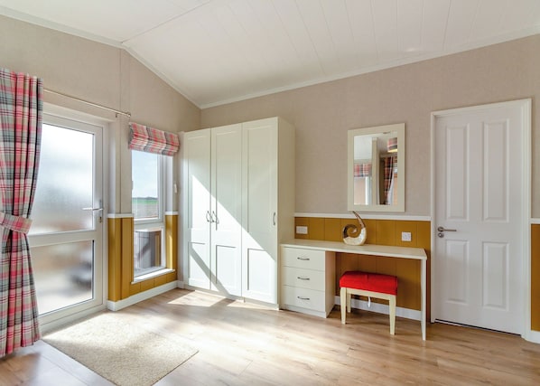Ein Zimmer mit Fenster, Tür, Spiegel, Schreibtisch und Stuhl.