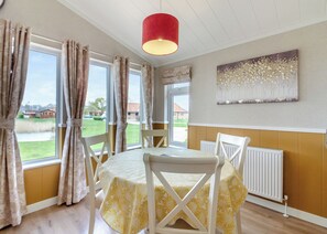 A dining area with a table set for four, a red pendant light, and a view of the outside.