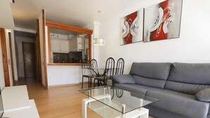 Una sala de estar moderna con una mesa de centro de vidrio, un sofá gris y una obra de arte abstracta en la pared.