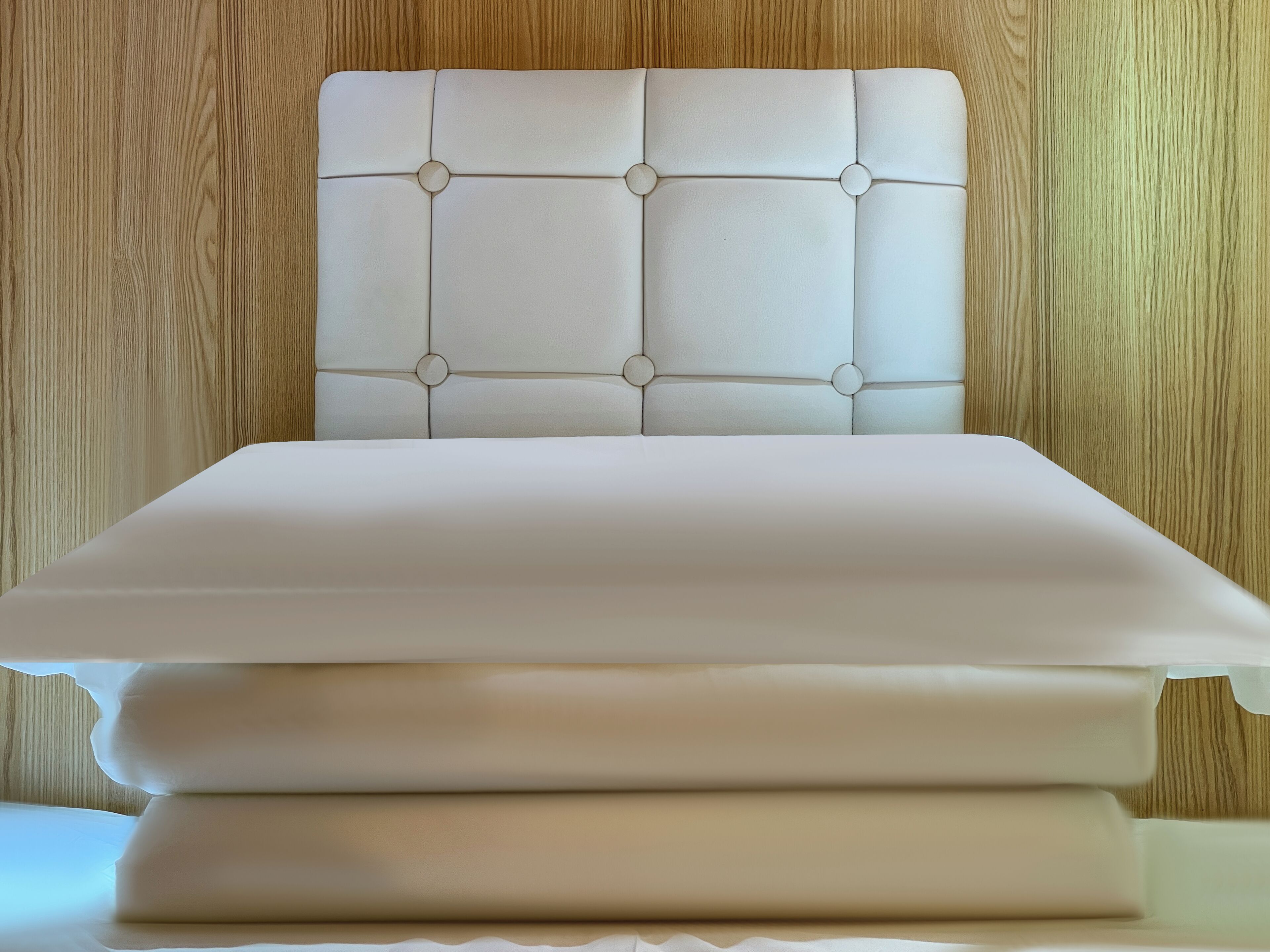 A bed with a tufted headboard and a neatly made white bedspread.