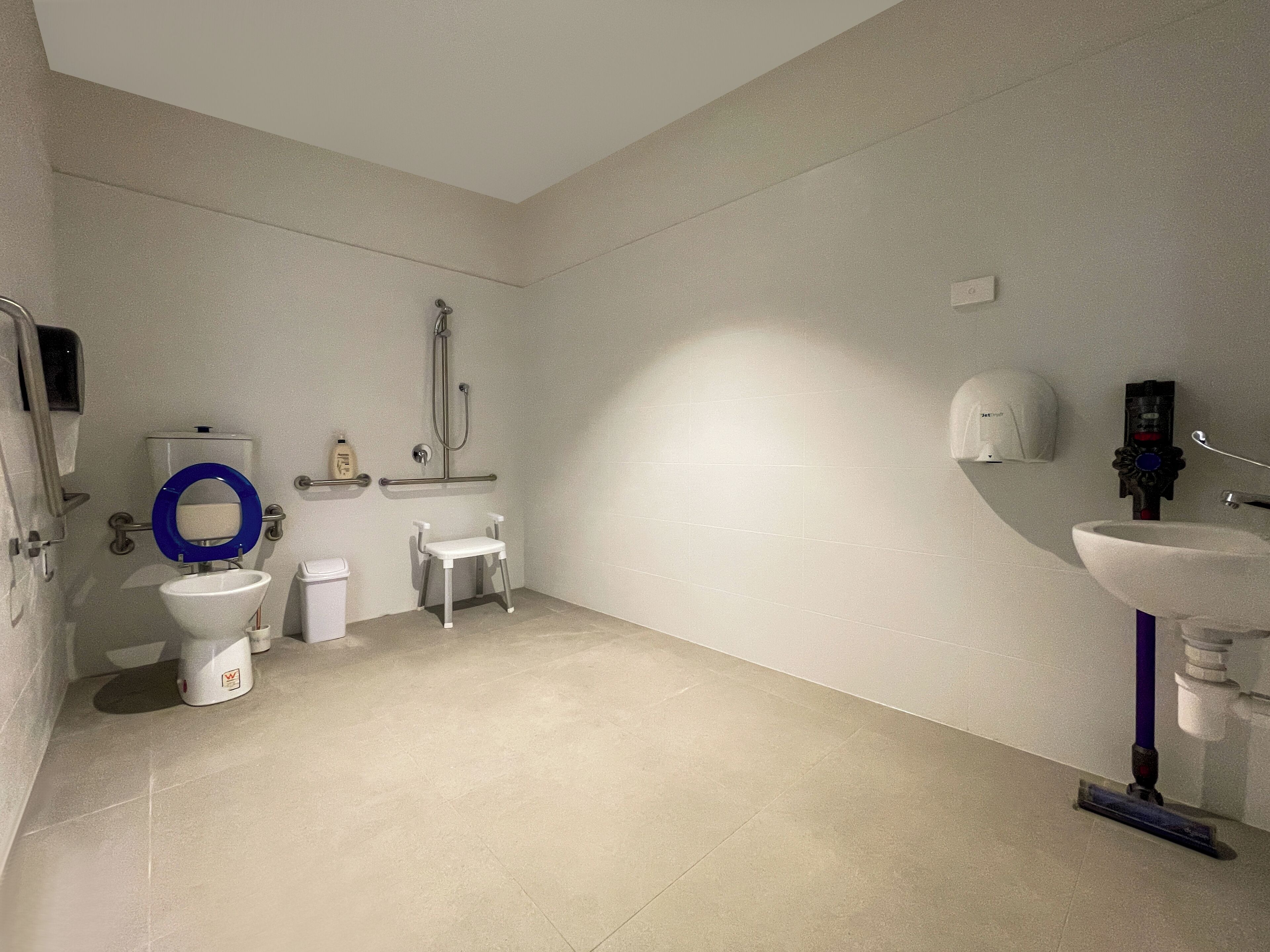 A modern bathroom with a toilet, bidet, shower, and sink.