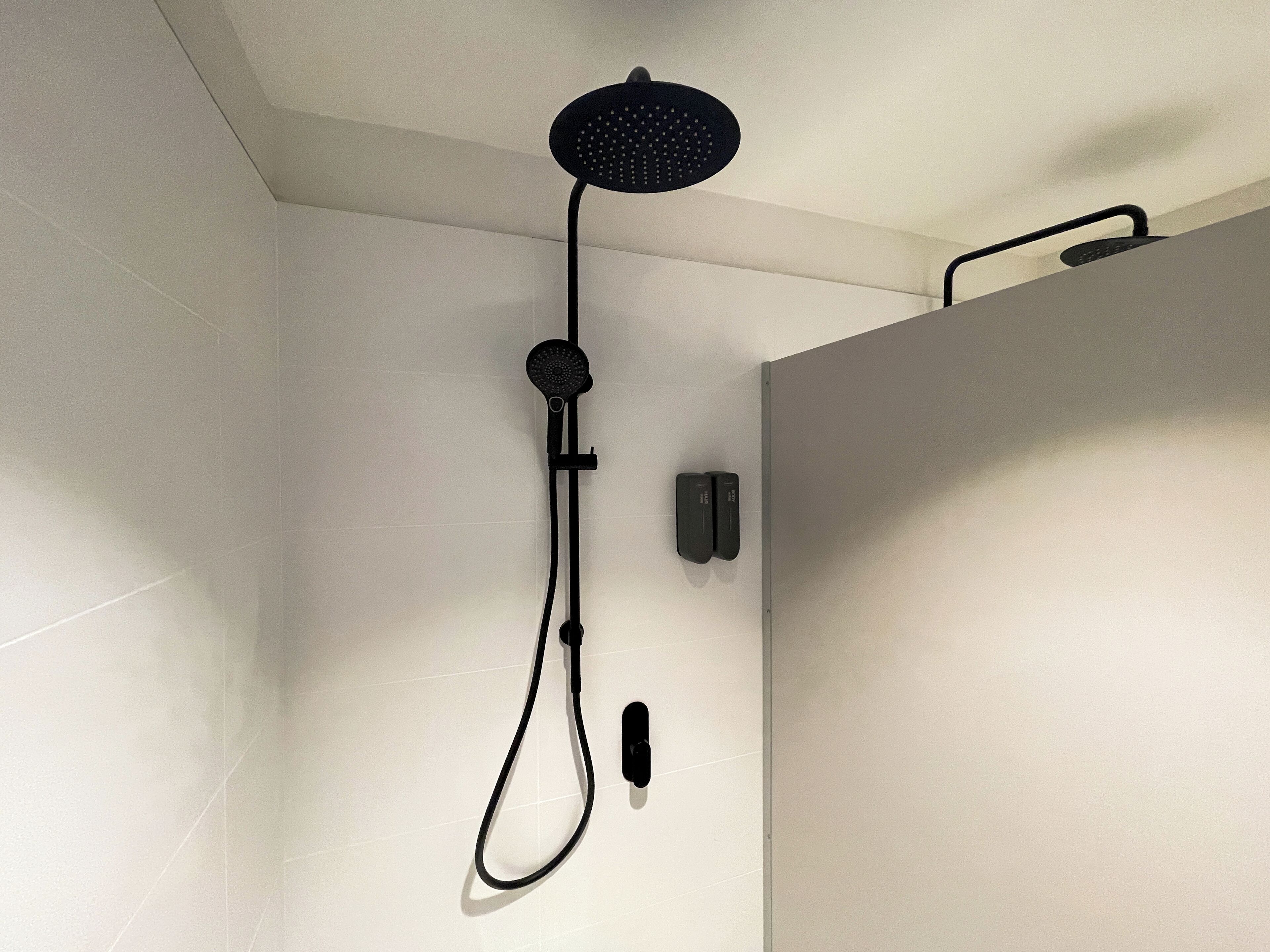 A modern shower with a handheld showerhead and a wall-mounted control panel.