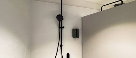 A modern shower with a handheld showerhead and a wall-mounted control panel.