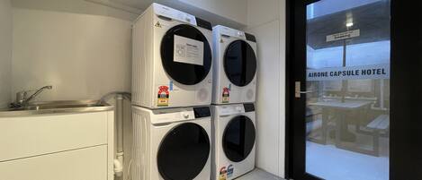 A laundry area with stacked washing machines and a sink.