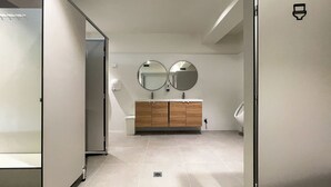 A modern bathroom with a toilet, bidet, and a vanity with a mirror. - Airone Capsule Hotel (Hobart)