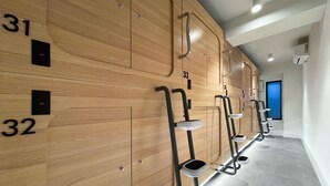 A row of wooden lockers with numbers 31, 32, 33, and 35, and metal step stools with built-in sinks. - Airone Capsule Hotel (Hobart)