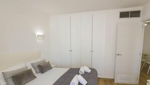 Un dormitorio con cama, armario blanco y una pequeña mesa con sillas.