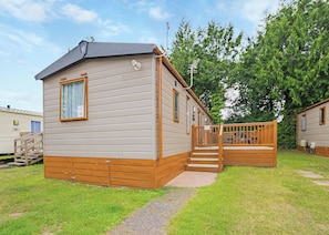 A mobile home with a deck, a window, and a door.