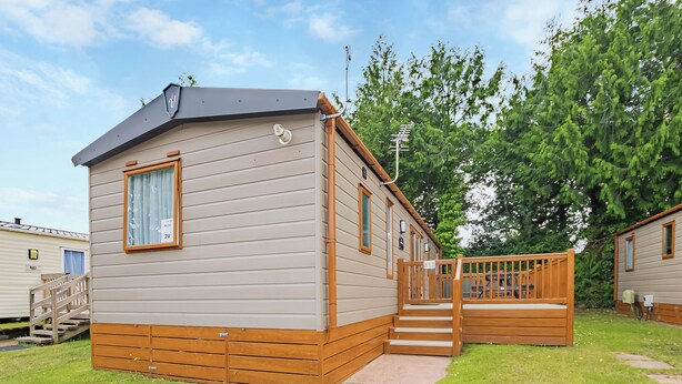 A mobile home with a deck, a window, and a door.