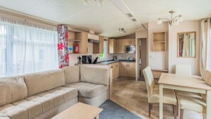 A compact living space with a sofa, a dining table, a kitchenette, and a small kitchen area.