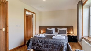 A bedroom with a bed, bedside lamps, a wooden door, and a window. - Outstanding, spacious and contemporary two storey lodge. (Hornsea)