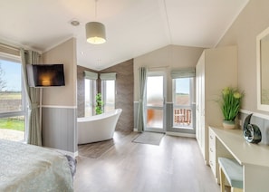 Ein Schlafzimmer mit einem großen Bett, einer Badewanne, einem Schreibtisch und einem Fernseher.