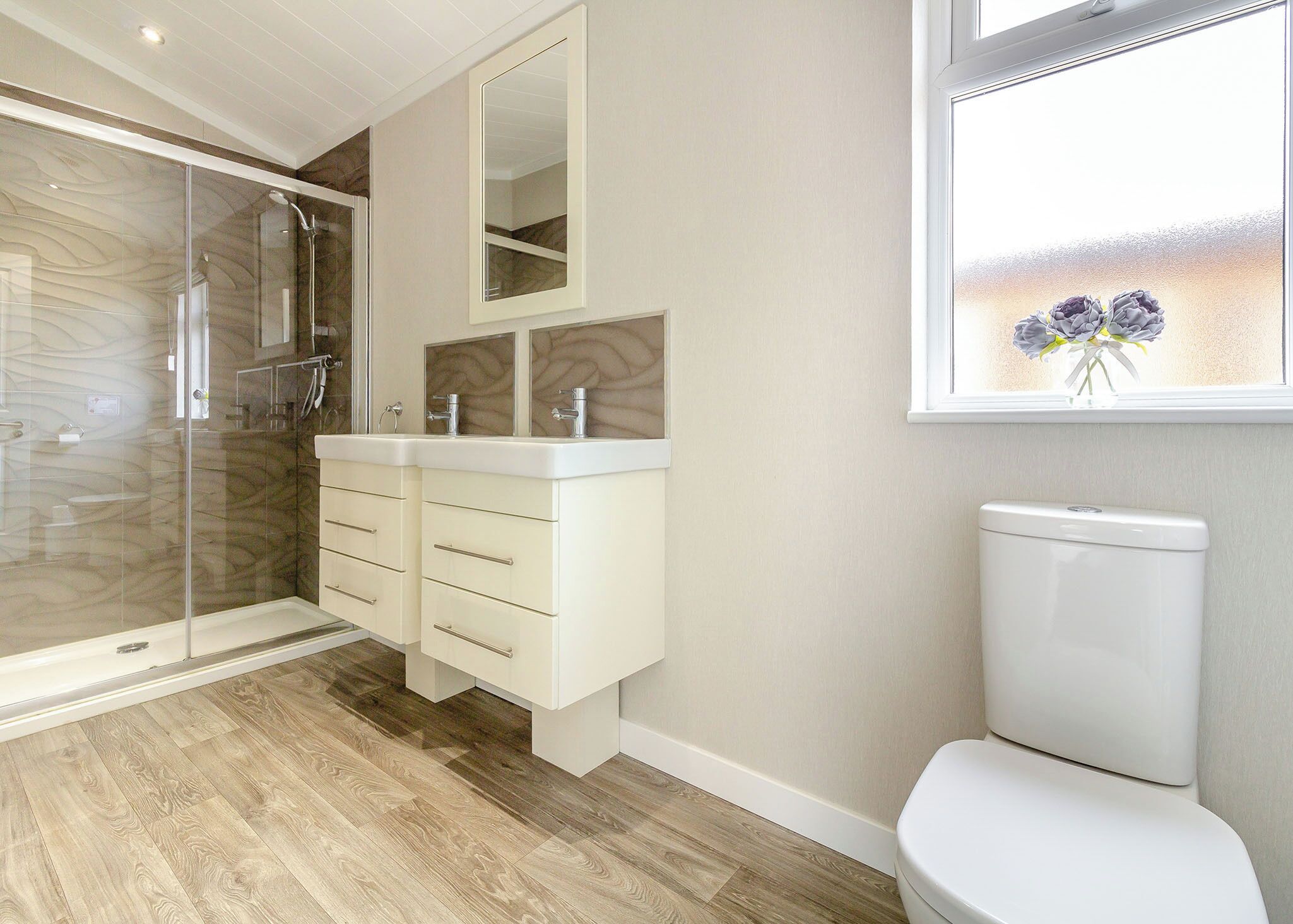 A modern bathroom with a glass shower enclosure, a white toilet, and a vanity with a mirror.
